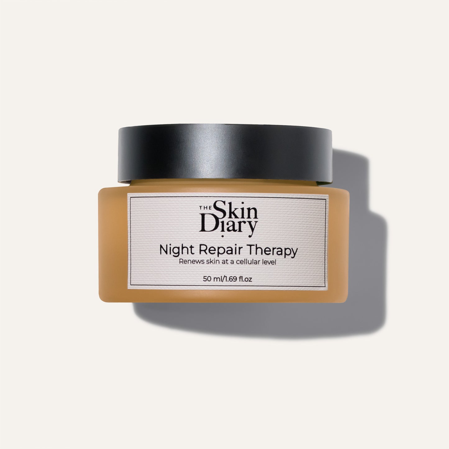 A jar of The Skin Diary Night Repair Therapy cream with a black lid and a amber glass container, shown on a white background with a soft shadow.