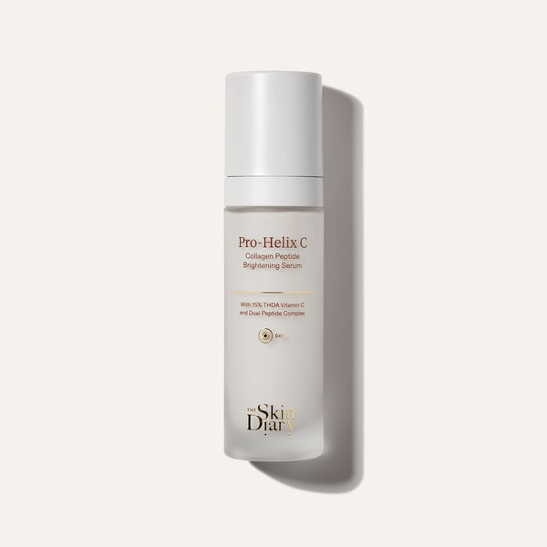 A frosted glass skincare bottle reading 'Pro-Helix C Collagen Peptide Brightening Serum' and 'The Skin Diary', set against a warm off-white background with a soft shadow.